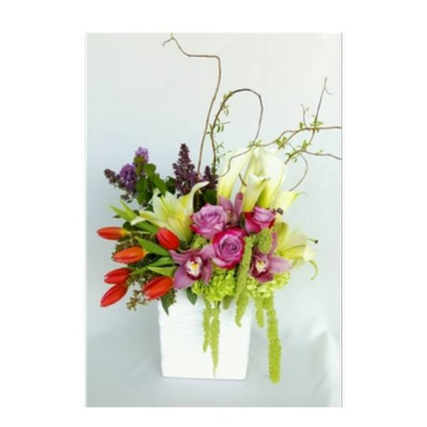 Colorful floral arrangement in a white square vase with tall branches