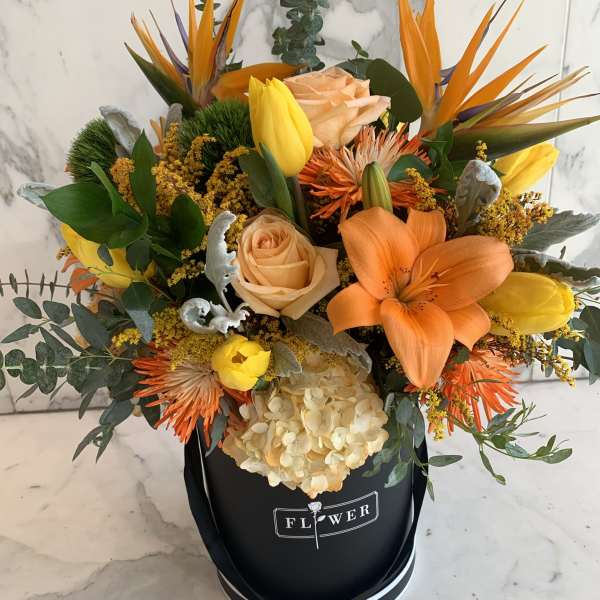 Bouquet of orange and yellow flowers in a black hat box
