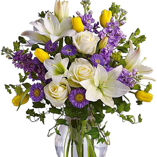 Bouquet of white lilies, roses, purple flowers, and yellow tulips in a glass vase