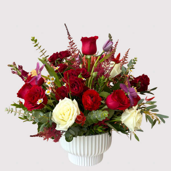 Red and white roses arranged in a white vase