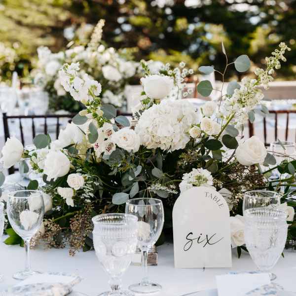 White floral centerpiece with roses and hydrangeas on a table