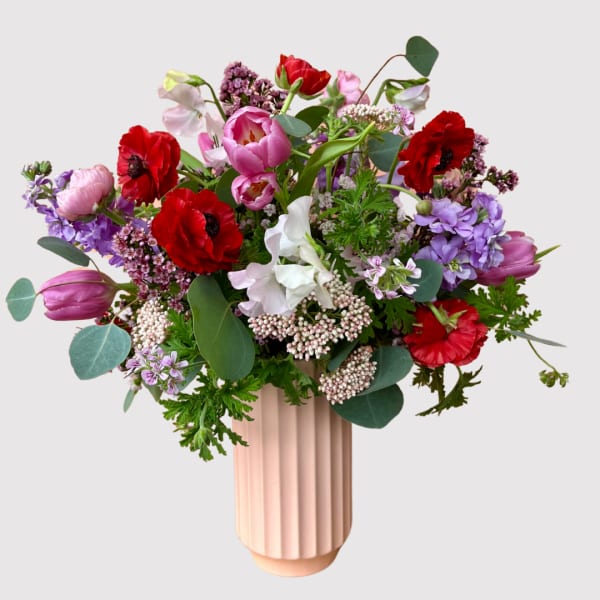 Mixed bouquet of red, pink, purple, and white flowers in a blush vase