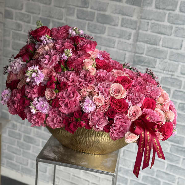 Large pink and red rose arrangement in a gold bowl