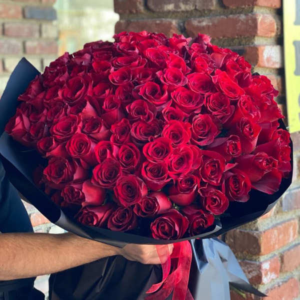 Large bouquet of red roses wrapped in black paper with a red ribbon