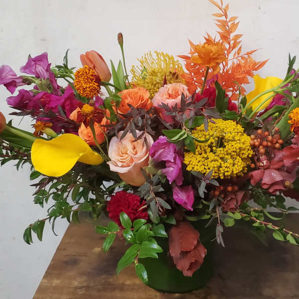 Mixed bouquet with roses, calla lilies, and bright orange and purple flowers in a vase