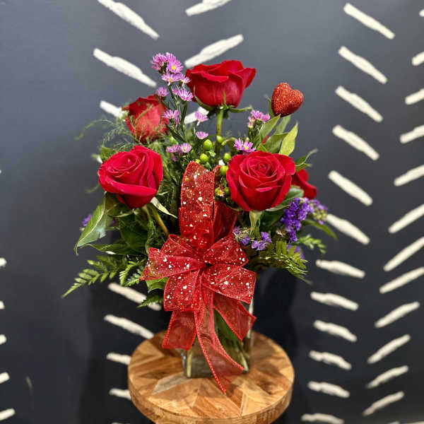 Bouquet of red roses with a glittery red bow in a glass vase