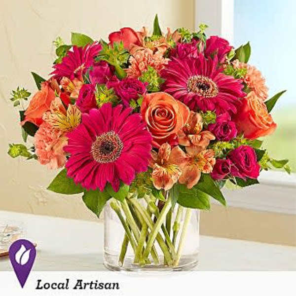 Mixed bouquet of pink and orange flowers in a clear glass vase