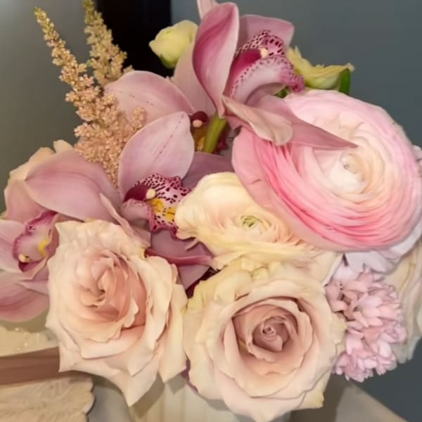 Pink and cream bouquet with roses, orchids, and ranunculus in a vase
