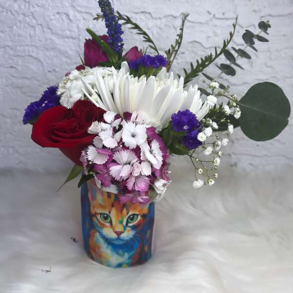 Mixed bouquet in a colorful cat-print vase with red and white flowers