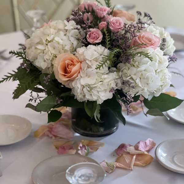 Pink and white floral centerpiece in a dark vase on a set table