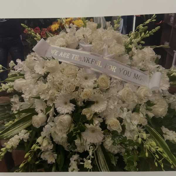 Large white sympathy floral spray with a thank-you ribbon