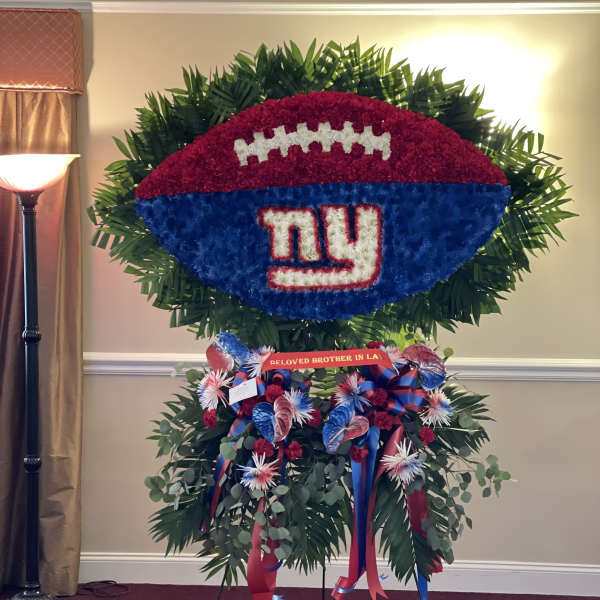 Large football-shaped floral tribute with a Giants logo and ribbon accents
