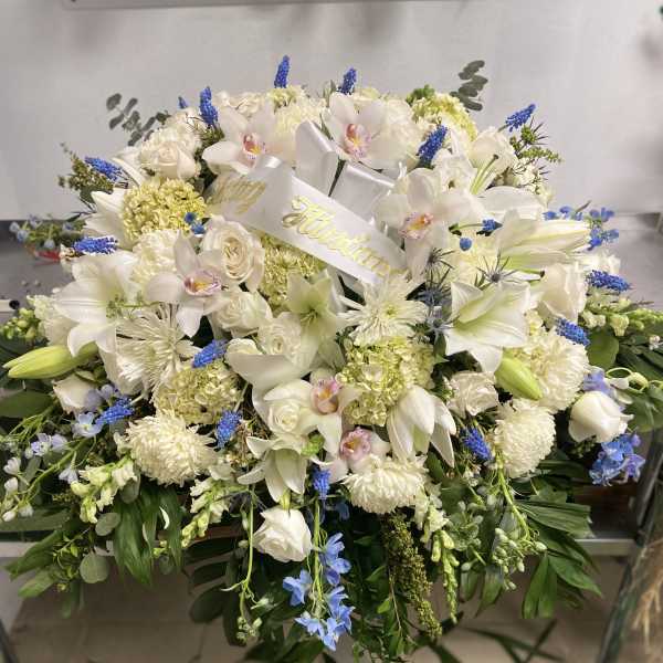 White floral spray with lilies, orchids, and blue accents