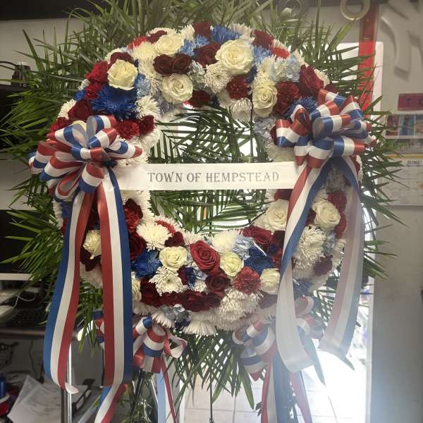 Large patriotic floral wreath with red, white, and blue flowers and ribbons