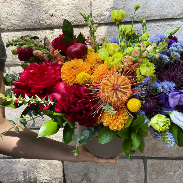 Colorful mixed bouquet in a round vase with red, orange, yellow, and purple blooms