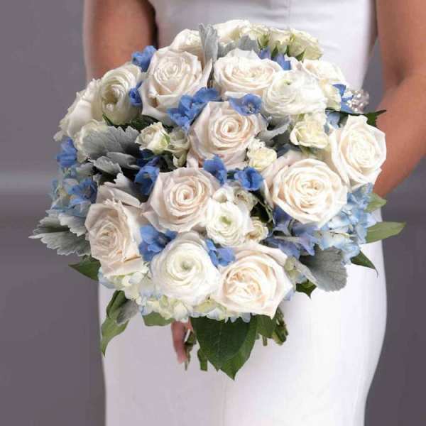 Bride holding a bouquet of white roses and blue flowers