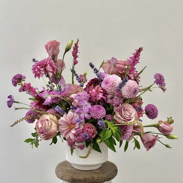 Pink and purple mixed flower arrangement in a white vase