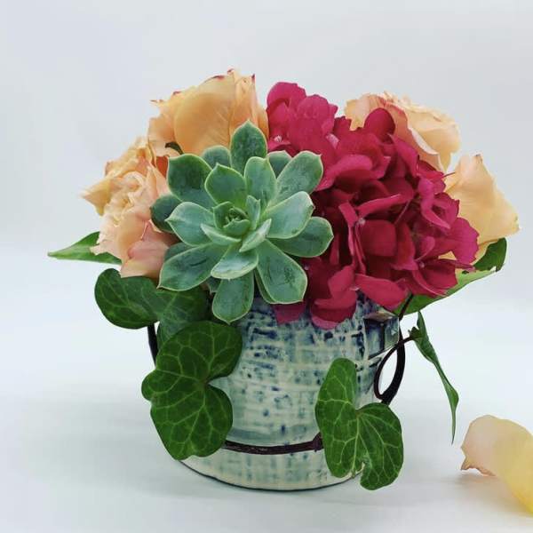 Succulent and pink flower arrangement in a blue ceramic pot