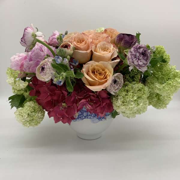Peach roses and pink hydrangeas in a white vase with green blooms