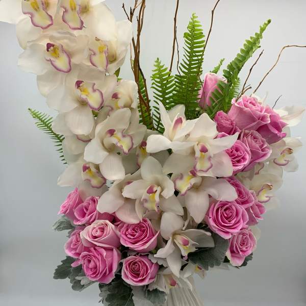 Pink roses and white orchids arranged in a ribbed white vase