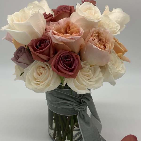 Bouquet of cream, blush, and burgundy roses in a glass vase