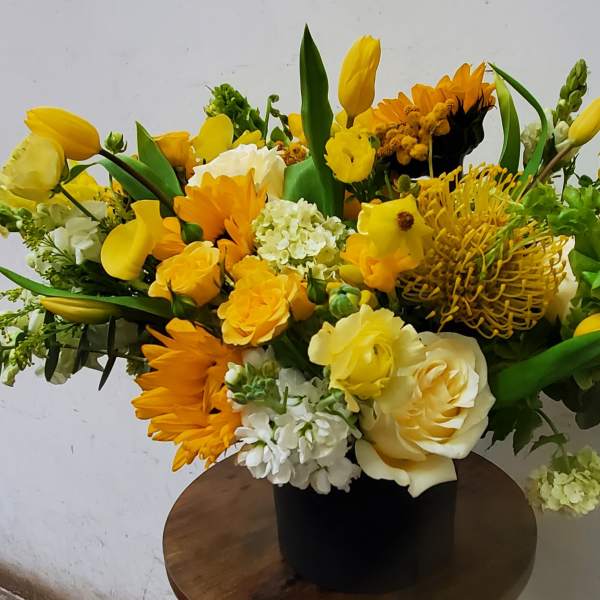 Yellow and white mixed flower arrangement in a black vase