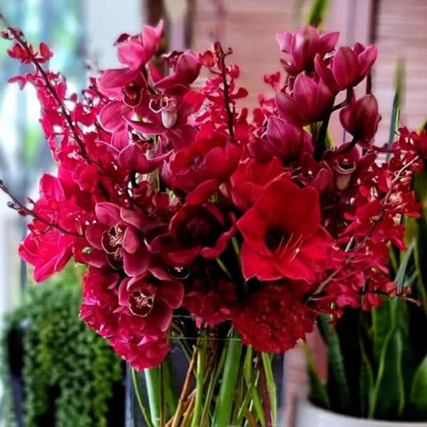 Bouquet of deep pink orchids and red flowers in a clear glass vase