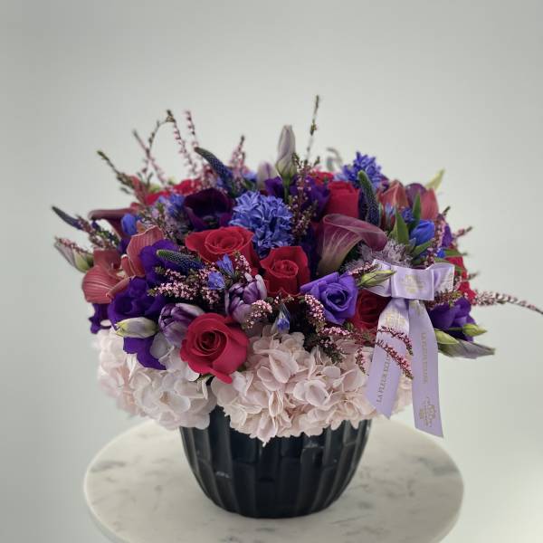 Mixed bouquet of pink, purple, and white flowers in a black vase