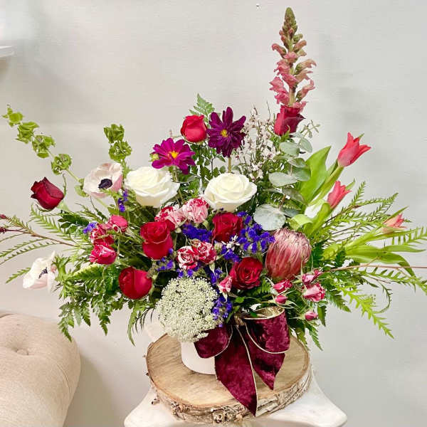 Large mixed bouquet with red, white, pink, and purple flowers in a white vase