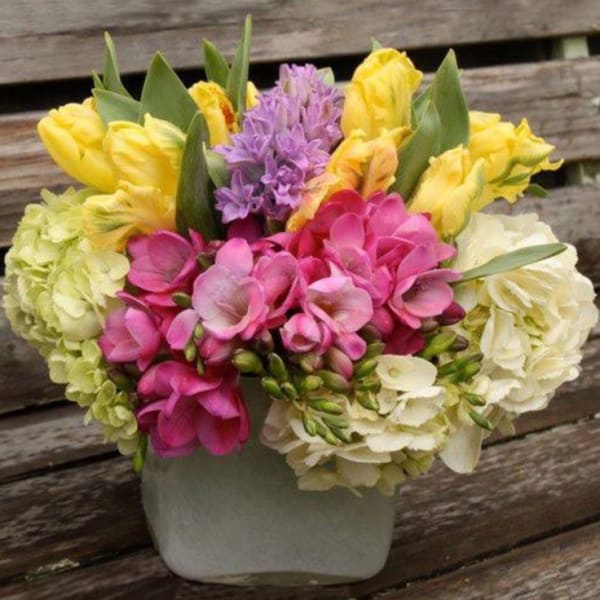 Bouquet of pink, yellow, and white flowers in a white vase