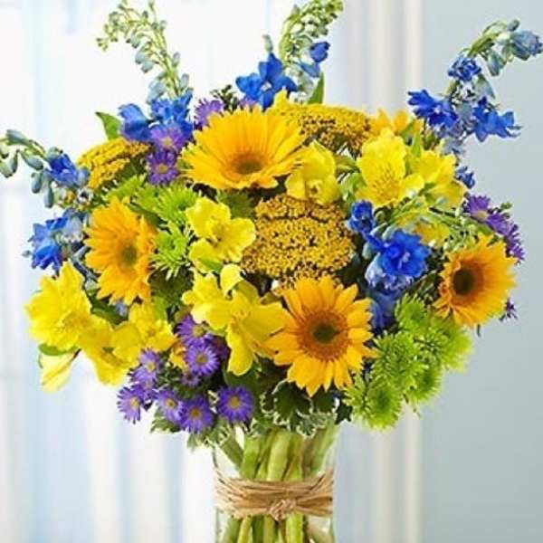 Bright mixed bouquet of yellow and blue flowers in a glass vase