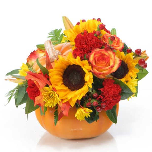 Autumn bouquet of sunflowers, roses, and carnations in an orange bowl vase