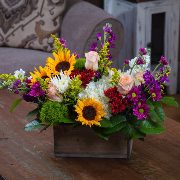 Mixed bouquet with sunflowers, roses, and purple blooms in a wooden box