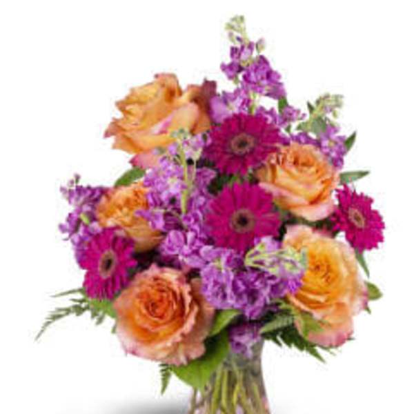 Bouquet of orange roses and purple daisies in a glass vase