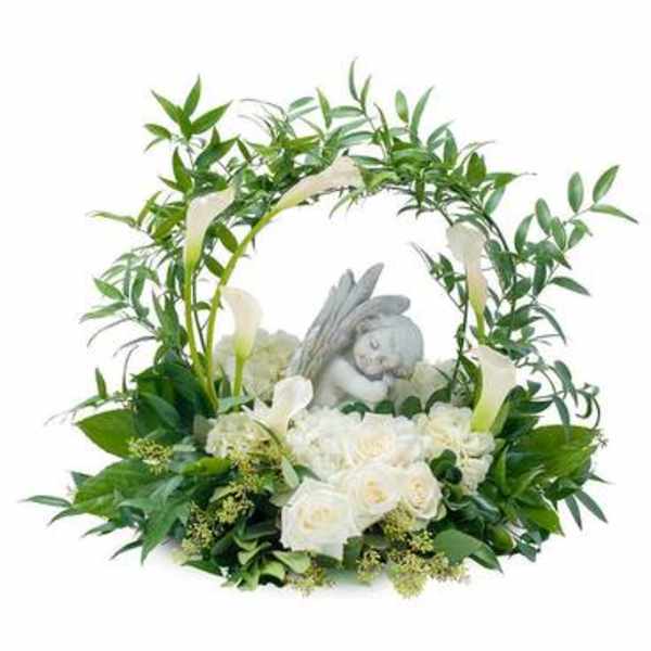 White roses and calla lilies arranged around a small angel figurine
