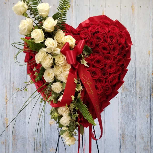 Heart-shaped bouquet of red and white roses with a red ribbon