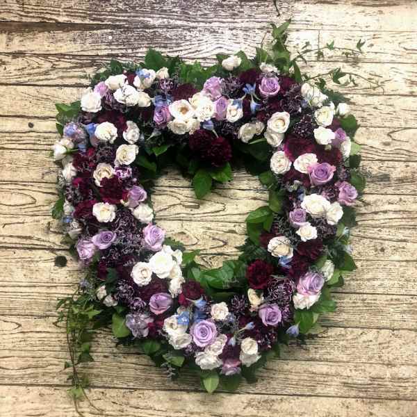 Heart-shaped floral wreath with purple, white, and burgundy roses