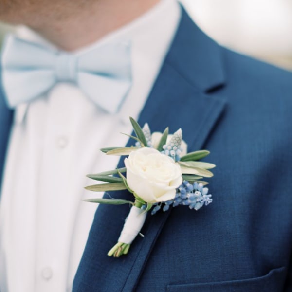 White boutonniere with blue accents pinned to a blue suit jacket