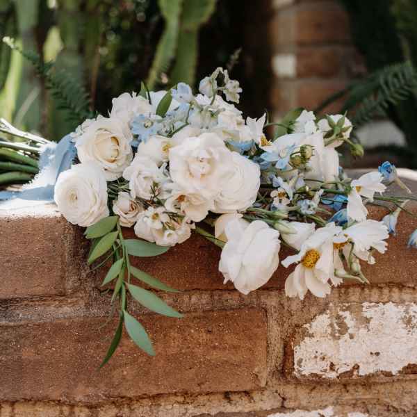 White and pale blue bridal bouquet on a brick ledge