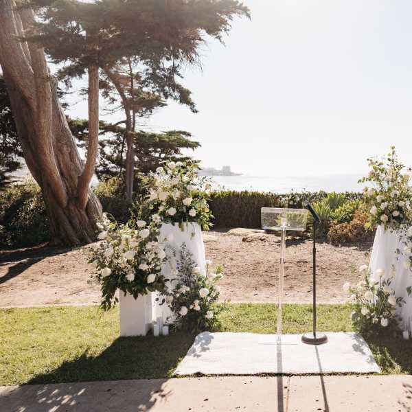 White floral wedding ceremony arrangements on pedestals by the ocean
