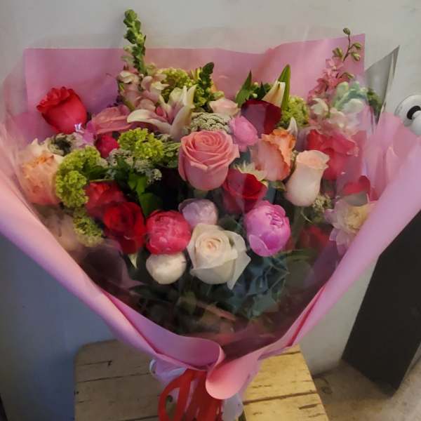 Bouquet of mixed roses and other flowers wrapped in pink paper