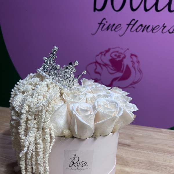White roses in a round box with a silver tiara and draping white filler