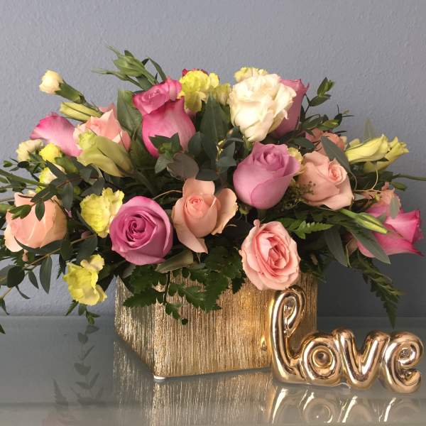 Pink and peach roses in a gold vase with a gold "love" decoration