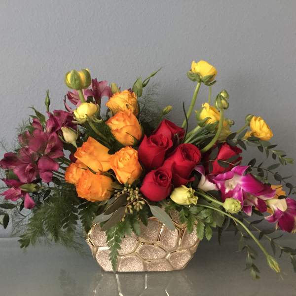 Mixed bouquet of roses and orchids in a gold textured vase