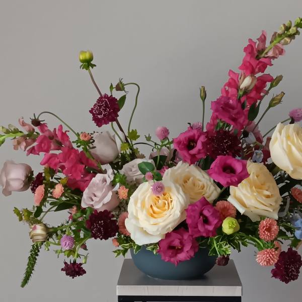 Mixed bouquet of pink and cream flowers in a blue vase