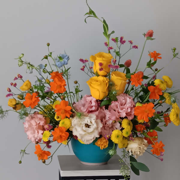 Colorful mixed bouquet in a blue vase with yellow roses and orange blooms