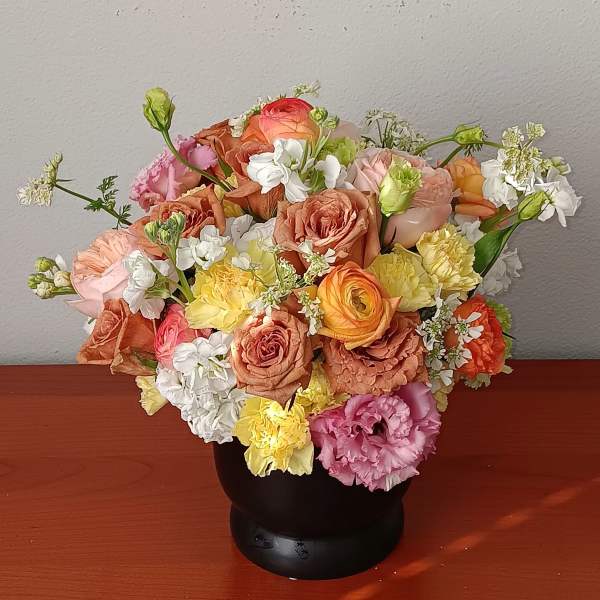 Mixed bouquet of pastel roses and carnations in a black vase