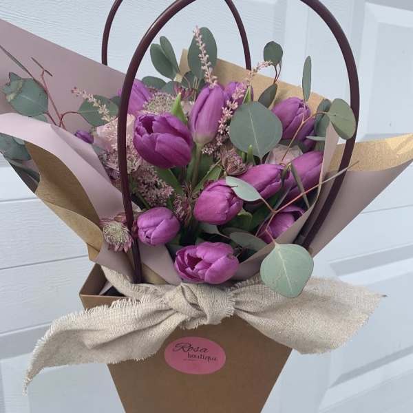 Bouquet of purple tulips wrapped in paper with eucalyptus