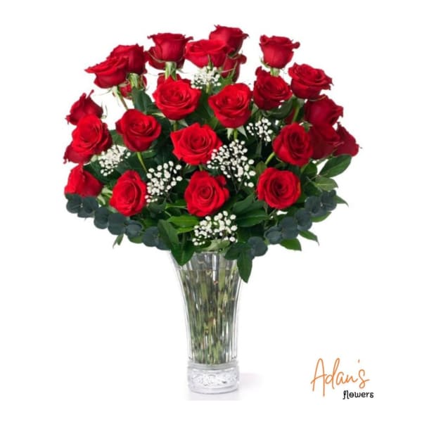 Red roses arranged in a clear glass vase with white filler flowers