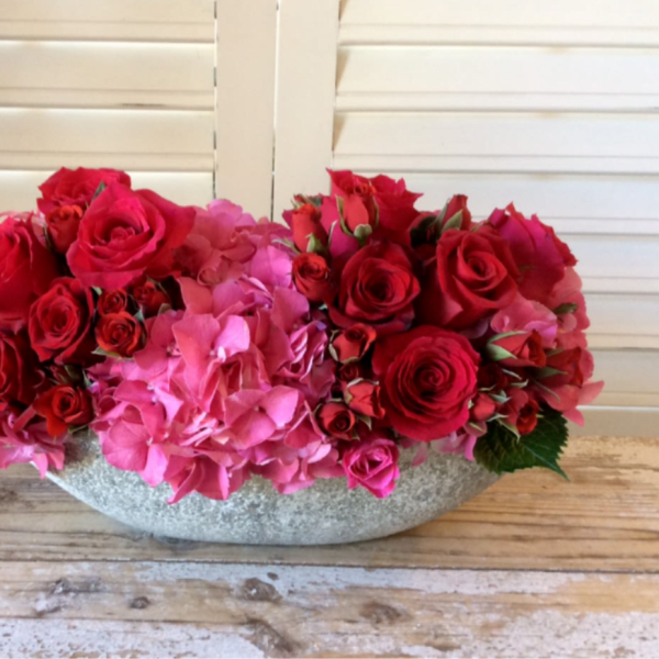 Red roses and pink hydrangeas in a low gray bowl